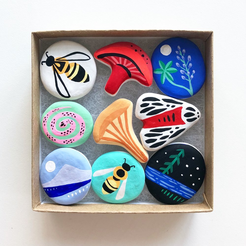 Painted rocks of bees, mushrooms, flowers, etc done by Lauren Blair